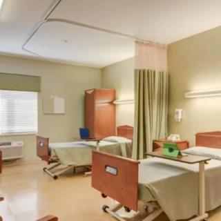 An empty hospital room with two beds and curtains, ready for patient care.