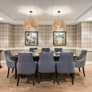 A stylish dining room with a table and eight chairs, decorated with two pieces of artwork and modern lighting fixtures.