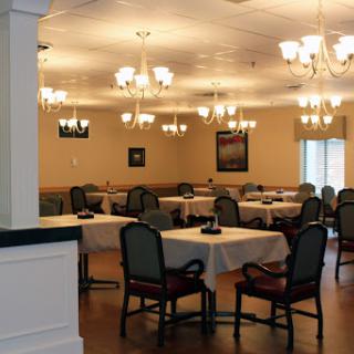 A spacious dining room featuring elegant chandeliers and set tables.