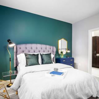 A modern bedroom with a teal accent wall, featuring a plush bed and contemporary decor.
