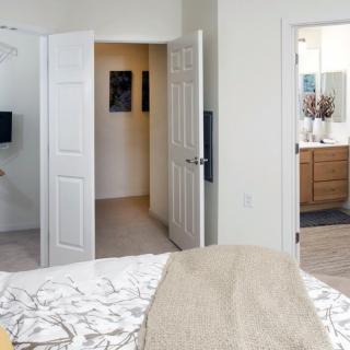 A modern bedroom with an open view into a bathroom and hallway.