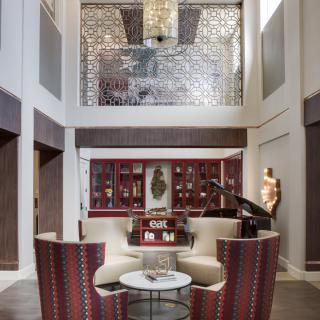 A luxurious living room with modern furniture, featuring a chandelier and intricate wall decor.