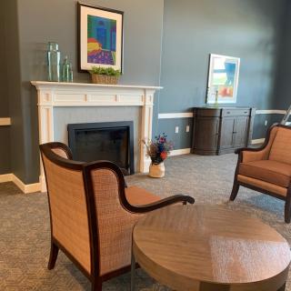 A cozy living room with a fireplace, elegant chairs, and modern artwork on the walls.