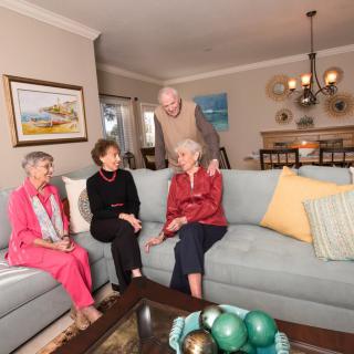 A group of elderly individuals sitting and conversing in a cozy living room setting.