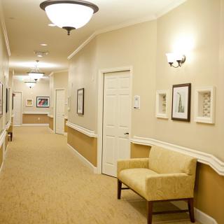 A well-lit hallway with a chair and framed pictures on the walls.