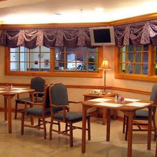 A cozy waiting area with chairs, tables, a lamp, and a television.