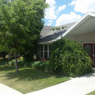A suburban house with a well-maintained lawn and trees under a partly cloudy sky.