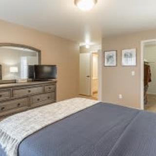 A cozy bedroom featuring a bed, dresser with a mirror, and a television.