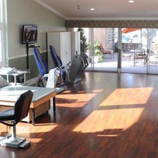 A well-lit physical therapy clinic with exercise equipment and a spacious interior.