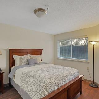 A cozy bedroom with a wooden bed frame, bedside tables, and a standing lamp near the window.