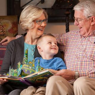 A happy moment as grandparents read a book with their young grandchild.