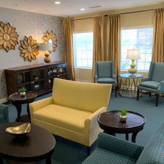 A cozy living room with a yellow sofa and blue chairs, featuring modern decor elements.