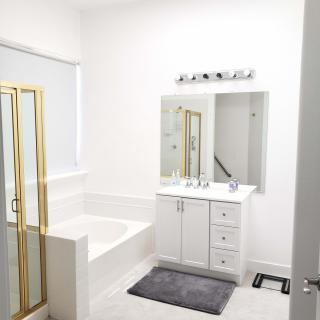 A modern bathroom with a bathtub, shower, and vanity featuring a large mirror.