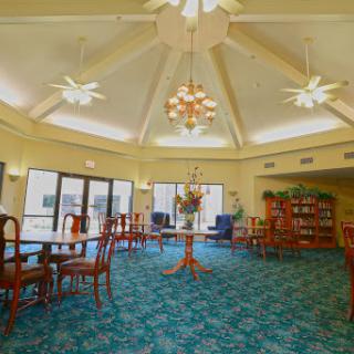 A spacious lounge area with elegant seating and abundant natural light, featuring ceiling fans and a cozy atmosphere.