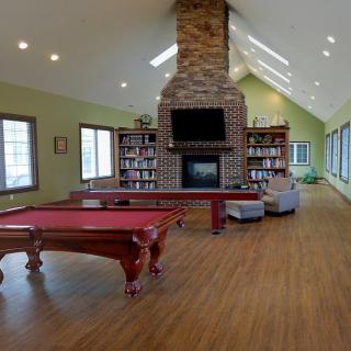 Spacious living room with a pool table and fireplace, surrounded by bookshelves.