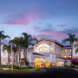 A beautiful residential building surrounded by palm trees at sunset.