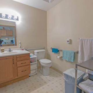 A modern bathroom with a vanity, sink, mirror, and toilet, featuring neatly arranged towels and a clean aesthetic.