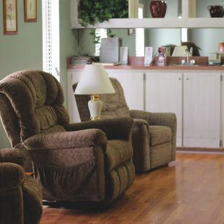 A cozy living room with plush armchairs and a lamp on a hardwood floor.