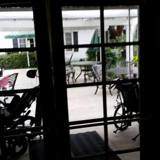 View of an outdoor patio area with tables, chairs, and bicycles seen through a window.