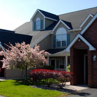A charming suburban house with a blooming tree and well-maintained landscaping.