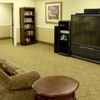 A cozy living room with a large television, bookshelf, and comfortable seating.