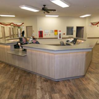 A modern office reception area with a large central desk and computer equipment.