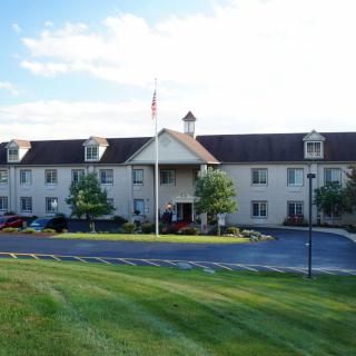 A hotel building with a well-kept lawn and a parking lot in front.