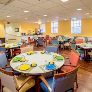 A brightly colored dining room with neatly set tables and chairs, ready for guests.