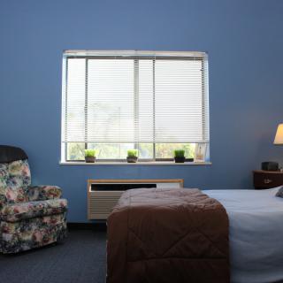 A simple bedroom with a chair, bed, and window.
