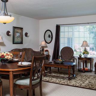 A cozy living and dining area with vintage furnishings and natural light.