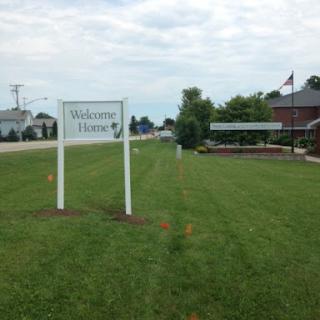 A welcoming sign in a grassy area, indicating the entrance to a facility.