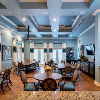 A spacious and elegantly designed dining area featuring round tables, comfortable chairs, and vibrant artwork on the walls.
