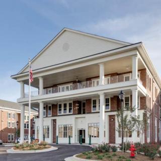 A colonial-style building with a prominent entrance and balconies, featuring a flagpole in front.