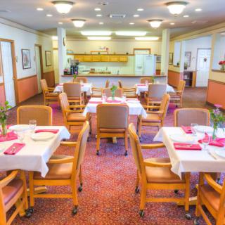 A well-lit dining room with neatly arranged tables and chairs, ready for service.