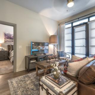 A modern living room with comfortable seating, a TV, and large windows.