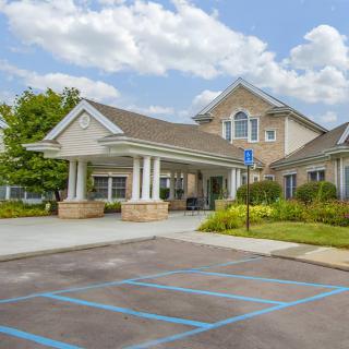 A residential building with a driveway and parking lot under a partly cloudy sky.
