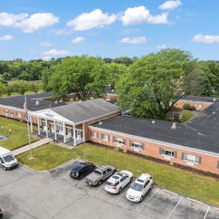 Aerial view of an educational institution surrounded by greenery and featuring a parking lot.