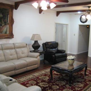 A cozy living room featuring a beige sofa, black armchair, and ornate coffee table on a patterned rug.