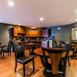 A cozy dining area connected to a kitchen with wooden furniture and flooring.