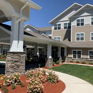 A modern residential building with well-maintained landscaping and a clear blue sky.
