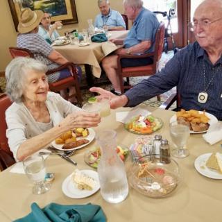 Elderly individuals enjoying a meal together in a dining setting.
