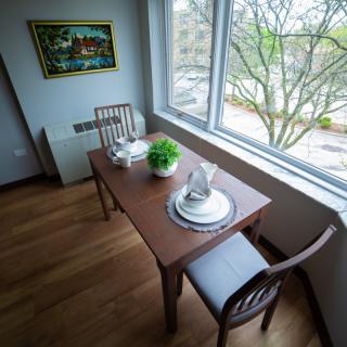 A cozy dining area with a wooden table set for two near a large window.