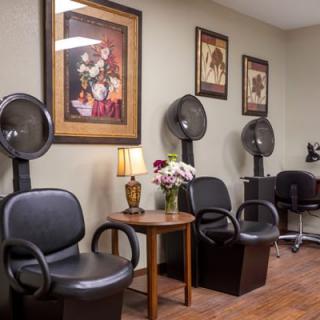 A cozy salon waiting area featuring hair dryers, comfortable chairs, and decorative wall art.