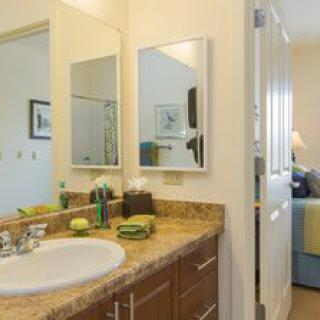 A clean and well-organized bathroom with a sink, mirror, and neatly arranged towels.