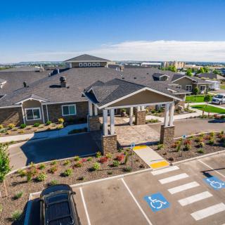 Aerial view of a modern building with an entrance and parking lot in a suburban area.