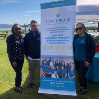 A group of individuals standing in front of a promotional banner at an outdoor event.