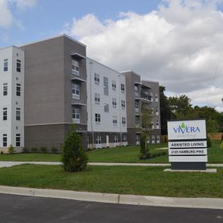 A modern apartment complex with a sign in front and well-maintained landscaping.
