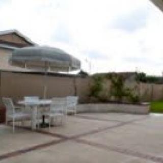 A backyard patio with a table, chairs, and an umbrella.