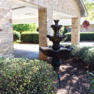 A tranquil garden scene featuring a decorative fountain surrounded by lush greenery.