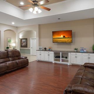 A spacious living room with leather sofas, a large TV mounted on the wall, and hardwood flooring.